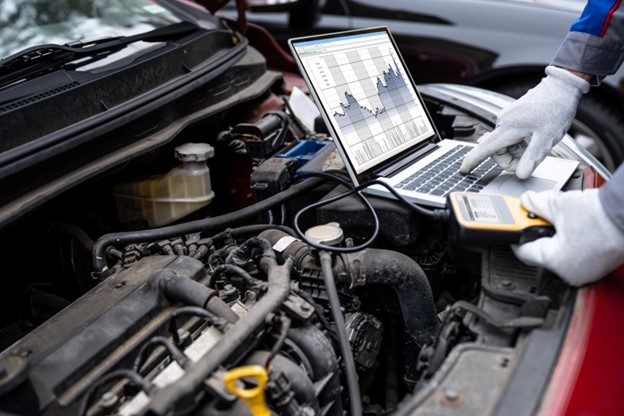 Under the hood of a car with someone running a diagnostic scan